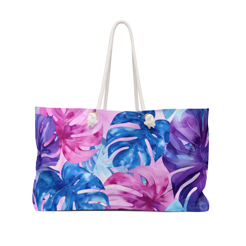 A Weekender Bag with Blue, Pink and Purple Monstera leaves